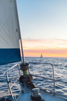 a sailboat sailing in the ocean at sunset