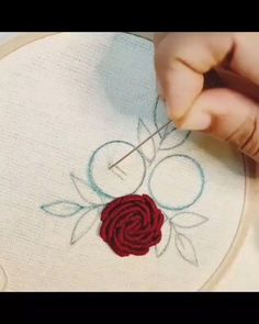 someone is stitching a rose on a piece of fabric