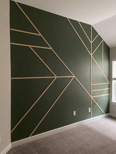 an empty room with green walls and gold lines painted on the wall, along with carpeted flooring