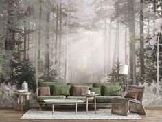 a living room with a green couch and coffee table in front of a forest wall mural