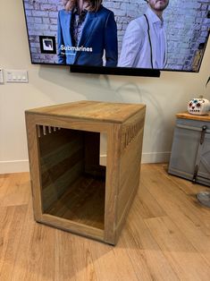 a dog crate sitting in front of a tv on the wall next to a wooden floor