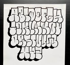 the letters are drawn in black and white on a piece of paper that has graffiti written all over it