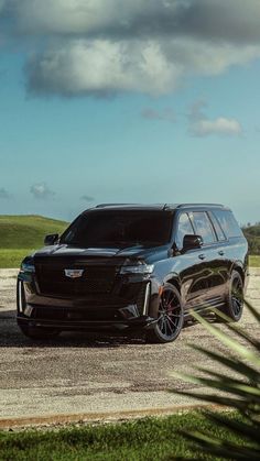 a black suv parked on top of a gravel road