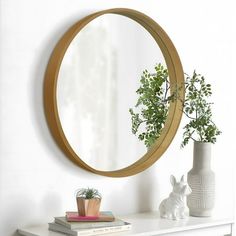 a white dresser topped with a mirror next to a plant and potted plant on top of it