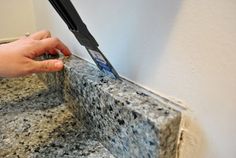 a person cutting something with a scissor on the edge of a counter top