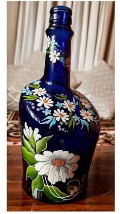 a blue vase with white flowers painted on it sitting on a table next to a bed