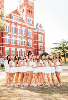 a group of young women standing in front of a red brick building with their arms around each other