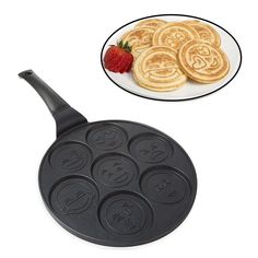 a pan with some pancakes on it next to a plate with strawberries and cookies