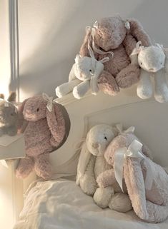 three stuffed animals sitting on top of a white bed next to a wall mounted mirror