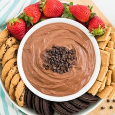 chocolate dip surrounded by cookies and strawberries on a platter