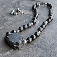 One of 9 unique handmade necklaces with raw black obsidian. It is decorated with stones with a diameter of 8 mm - polished and matt onyx. The dividers are made of silver hematites and the ends are decorated with smaller black onyx stones. All stones are 100% natural, yet it is very light and comfortable to wear. The necklace is made of a strong black string and is adjustable in length (macrame sliding knot) - it can be worn both as a long necklace and as a choker. It is waterproof - none of the Black Obsidian Necklace With Natural Stones, Unique Black Jewelry With Gemstone Beads, Unique Black Agate Jewelry, Lava Stone Necklace With Natural Stones For Gift, Minimalist Black Necklace With Natural Stones, Black Agate Spiritual Necklace, Spiritual Black Necklace With Raw Stone, Adjustable Black Necklaces With Natural Stones, Adjustable Black Agate Necklace