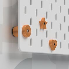 the pegs are attached to the white wall with orange handles and knobs on them