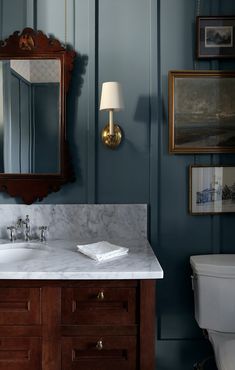 a bathroom with blue walls and white marble counter tops, along with a wooden vanity