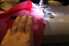 a woman is using a sewing machine to sew pink material with black dots on it