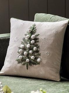 a christmas tree pillow on a green couch with white pom - poms around it