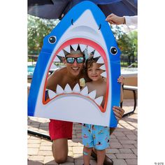 two people are posing with a fake shark