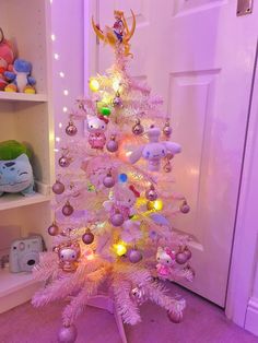 a pink christmas tree decorated with ornaments and lights