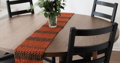 a wooden table topped with a vase filled with flowers and a crocheted runner