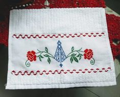 an embroidered piece of cloth with flowers and a cross on the front, sitting on a table