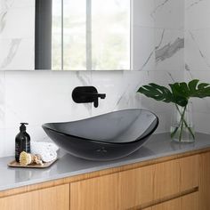 a black bowl sink sitting on top of a bathroom counter next to a mirror above it