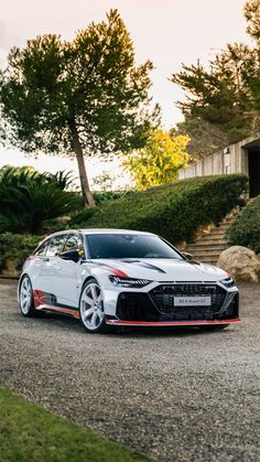 a white sports car parked in front of some bushes