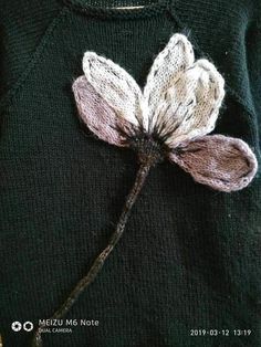 a close up of a sweater with a flower on it