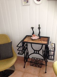 a sewing machine table with a bowl of food on it next to two yellow chairs