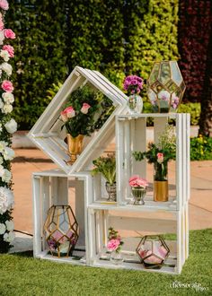 an assortment of vases and flowers are arranged on a shelf in the grass outside