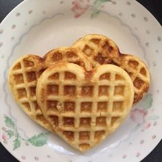 three heart shaped waffles on a plate with floral designs around the edges and bottom