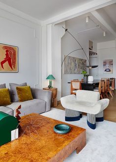 a living room filled with furniture and a painting on the wall above it's coffee table