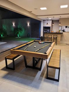 a pool table and two benches in a room with lights on the wall behind it