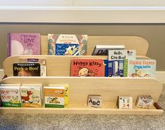 a wooden book shelf filled with books on top of a carpeted floor next to a wall