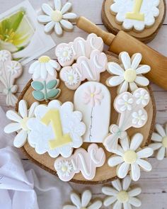 decorated cookies in the shape of numbers and flowers on a wooden platter with a rolling pin