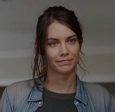 a close up of a person wearing a blue shirt and grey shirt with long hair