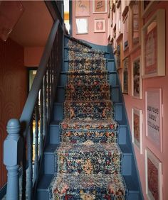 a blue stair case with pictures on the wall and carpeted steps leading up to it