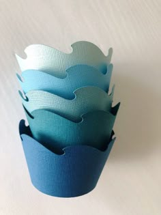 four blue cupcake cases are stacked on top of each other in the shape of waves