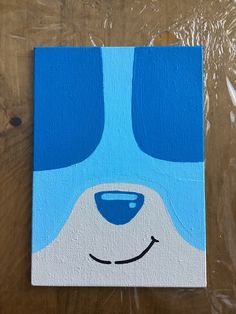 a painting of a dog's face with blue eyes on a wooden table top