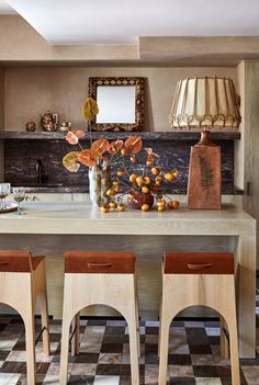 a dining room table with four chairs and a vase filled with oranges on it