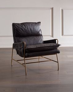 a black leather chair sitting on top of a hard wood floor next to a white wall