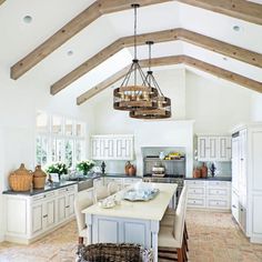 a large kitchen with white cabinets and wooden beams on the ceiling, along with a breakfast nook