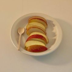 sliced apples in a white bowl with a spoon on the side, ready to be eaten