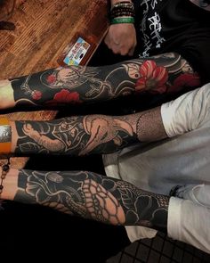 two men with tattoos on their arms and legs sitting next to each other at a table