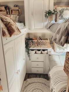 a bedroom with white cupboards and bedding in the corner next to a rug