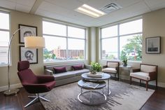 a living room with couches, chairs and tables in front of two large windows