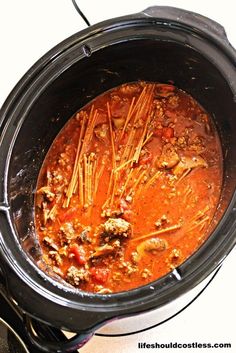 a crock pot filled with meat and vegetables on top of a stove burner