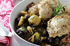 a white bowl filled with chicken, potatoes and brussel sprouts on top of a table