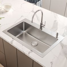 a stainless steel kitchen sink on a marble countertop