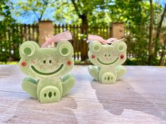 two ceramic frog figurines sitting on top of a wooden table