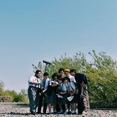 a group of people standing next to each other on top of a rocky ground with trees in the background