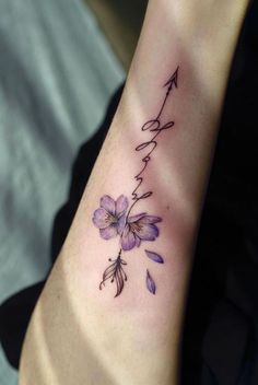 a woman's arm with flowers and an arrow tattoo on the left side of her wrist